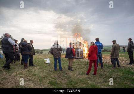 Eine Gruppe von Zuschauer, die ständigen Um einen beleuchteten Feuer Leuchtfeuer für 90 Queen's Geburtstag in Whitwell, Isle of Wight, Großbritannien Stockfoto