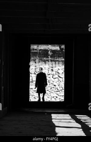 Silhouette des Mannes in traditionelle bhutanische Gho Outfit durchqueren historische bedeckt Freischwinger Brücke nach Paro Dzong, Bhutan Stockfoto