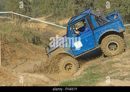 Blaues Auto tritt in eine Pfütze Schlamm auf ein trial Rennen Stockfoto