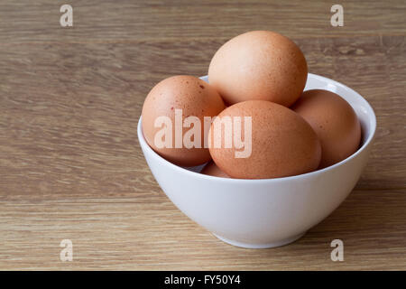 Eine weiße Schüssel voll mit frischem, gefleckte Eier auf einem Holztisch. Stockfoto