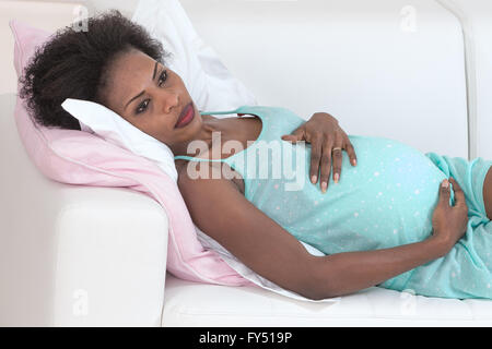 Schwangere Frau zu Hause auf Sofa entspannen Stockfoto