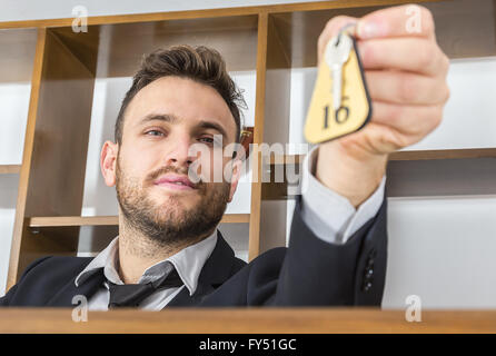 Bild der Empfangsdame an seinem Schreibtisch, geben den Schlüssel an einem Client. Selektiver Weichzeichner auf dem Gesicht. Stockfoto