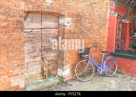 altes violettes Fahrrad geparkt lange eine Außenwand in Insel Burano, Venedig Stockfoto