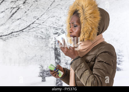 Closeup Portrait krank junge Afrikanerin mit Kapuzen-Mantel mit Fell, Nase Winter Hintergrund weht Stockfoto