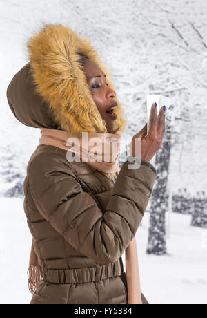 Closeup Portrait krank junge Afrikanerin mit Kapuzen-Mantel mit Fell, Nase Winter Hintergrund weht Stockfoto