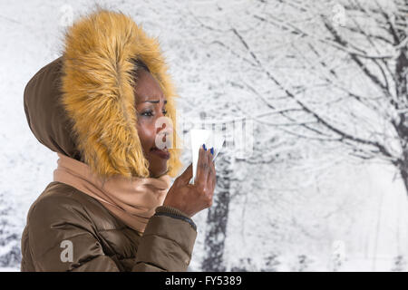 Closeup Portrait krank junge Afrikanerin mit Kapuzen-Mantel mit Fell, Nase Winter Hintergrund weht Stockfoto