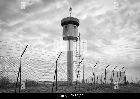 Verlassenen Wachturm isoliert durch ein Netz mit Stacheldraht gekrönt. Stockfoto