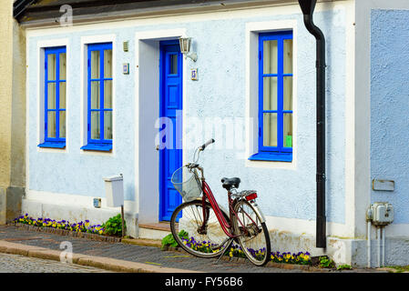 Trelleborg, Schweden - 12. April 2016: Fahrrad vor einem Pastell gemalte blaue und weiße Wohnhaus geparkt. Blumenbeet mit pansi Stockfoto