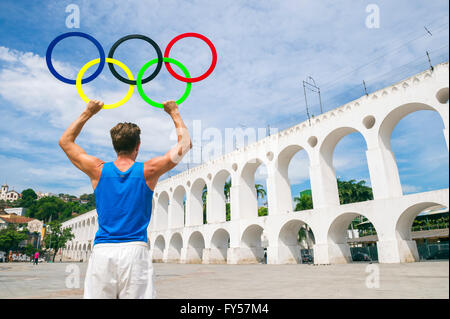 RIO DE JANEIRO - 29. März 2016: Sportler der Olympischen Ringe steht im Freien in der Plaza in das Wahrzeichen Lapa Bögen halten. Stockfoto