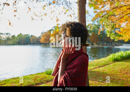 Frau Musik hören im Herbst Park bei Sonnenuntergang mit Kopfhörer Stockfoto