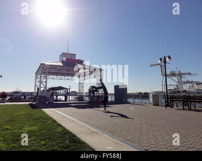 Mann macht Handstand vor Ferry Terminal teilen seine Beine, in der Jack London Square in Oakland mit Lense Flare auszugleichen. Stockfoto