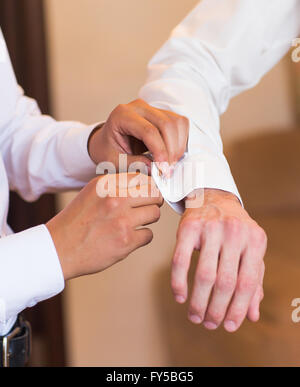 Brautführer hilft Bräutigam auf Manschettenknöpfe Nahaufnahme Stockfoto