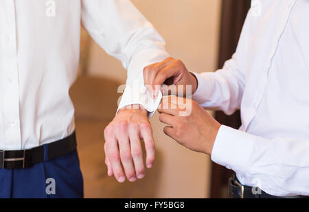 Brautführer hilft Bräutigam auf Manschettenknöpfe Nahaufnahme Stockfoto