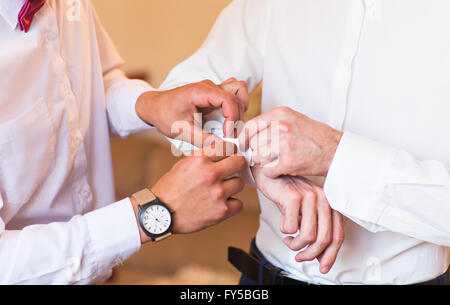 Brautführer hilft Bräutigam auf Manschettenknöpfe Nahaufnahme Stockfoto