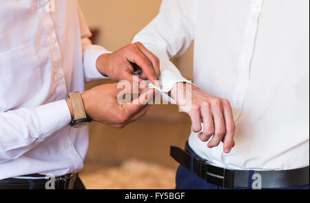 Brautführer hilft Bräutigam auf Manschettenknöpfe hautnah Stockfoto