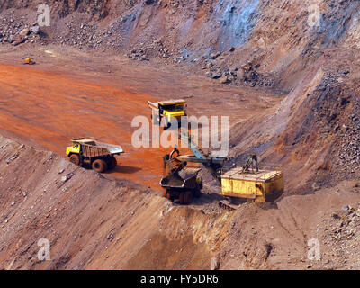 Steinbruch Bagger laden das Eisenerz zu große Muldenkipper in Openpit mir mit einem anderen zwei Lastwagen in Warteschlange Stockfoto