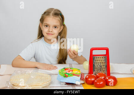 Sechsjährigen Mädchen sitzen am Küchentisch vor ihr sind Gemüse, Base und andere Zutaten für pizza Stockfoto