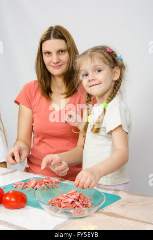 Sechs Jahres altes Mädchen hilft Mutter kochen auf dem Küchentisch Stockfoto