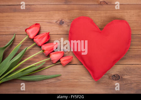 Strauß Tulpen und Herz auf einem hölzernen Hintergrund liegen. Stockfoto