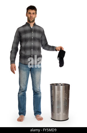 Junger Mann, der schmutzige Socken in einen Wäschekorb, isoliert auf weiss Stockfoto