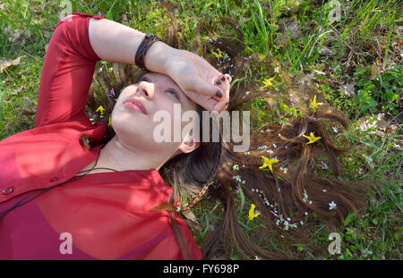 Porträt des jungen Mädchens Verlegung auf Rasen mit kleinen Blumen im Haar Stockfoto