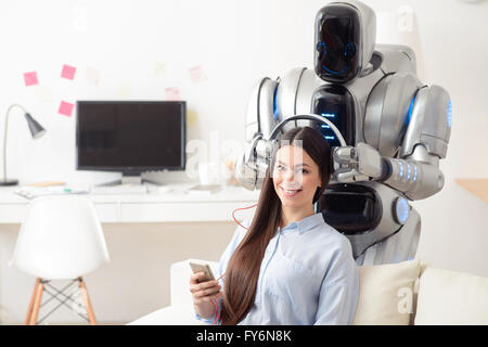 Moderne Roboter mit Kopfhörern auf lächelnde Mädchen Stockfoto