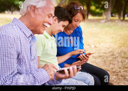 Ältere Mann und Frau lernen, Internet und Handy: junges Kind helfen, seine Großeltern, Surfen im Internet mit ihrer neuen Mobi Stockfoto