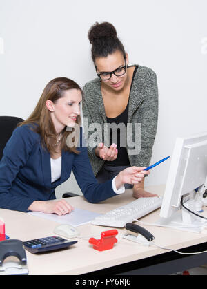 Zwei Business-Frauen diskutieren vor dem Computer im Büro. Beide Frauen sind auf der Suche auf den Monitor. Eine Frau ist po Stockfoto