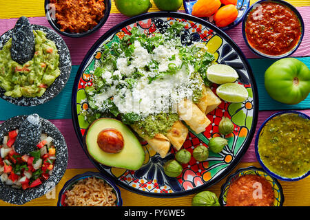 Mexikanisches Essen grüne Enchiladas mit Guacamole und Saucen auf bunten Tisch Stockfoto