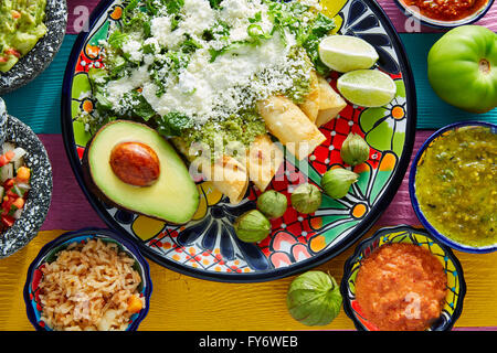 Mexikanisches Essen grüne Enchiladas mit Guacamole und Saucen auf bunten Tisch Stockfoto