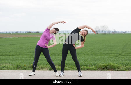 zwei Frauen, 20 bis 40 Jahre alten stretching (dabei Sport) im freien Stockfoto