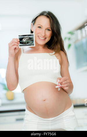 Schwangere Frau hält ein Ultraschallbild Stockfoto