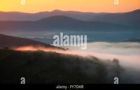 Blick auf ein Tal im frühen Morgen mit Nebel zwischen Hügeln Stockfoto