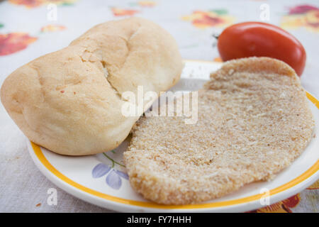 ungekocht Kalbsschnitzel mit einem Brötchen und frischen Tomaten Stockfoto