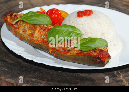 Gefüllte Zucchini, Reis, geschmorte Paprika und Tomaten, Gemüse, Beilagen, garniert mit Basilikum-Blätter auf einer Platte Stockfoto