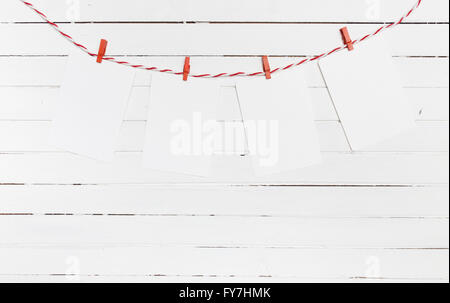 Leeres Papier oder Foto Rahmen rot gestreiften Wäscheleine hängen. Auf hölzernen Hintergrund. Vorlage für Ihren Text. Stockfoto