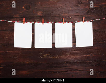 Leeres Papier oder Foto Rahmen rot gestreiften Wäscheleine hängen. Auf hölzernen Hintergrund. Vorlage für Ihren Text. Stockfoto