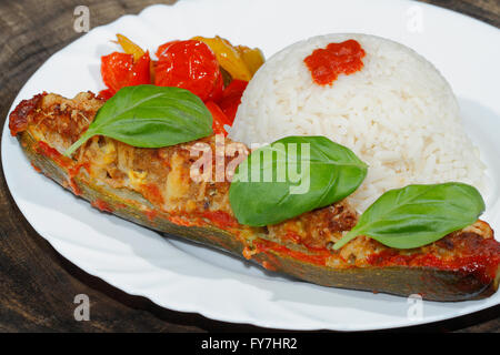 Gefüllte Zucchini, Reis, geschmorte Paprika und Tomaten, Gemüse, Beilagen, garniert mit Basilikum-Blätter auf einer Platte Stockfoto