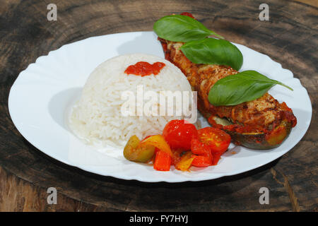 Gefüllte Zucchini, Reis, geschmorte Paprika und Tomaten, Gemüse, Beilagen, garniert mit Basilikum-Blätter auf einer Platte Stockfoto