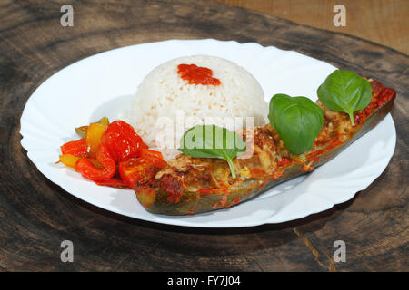 Gefüllte Zucchini, Reis, geschmorte Paprika und Tomaten, Gemüse, Beilagen, garniert mit Basilikum-Blätter auf einer Platte Stockfoto