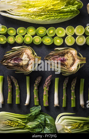 Grünes Gemüse halbieren, flach legen Design auf dunklem Hintergrund, symmetrisch. Stockfoto