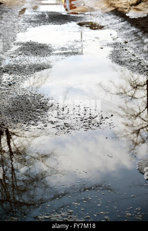 Mit Wasser gefüllte Schlaglöcher auf Asphaltstraße Stockfoto