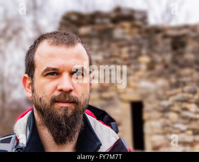 Blauäugige bärtiger Mann Nahaufnahme vor einer steinernen Burgruine. Stockfoto