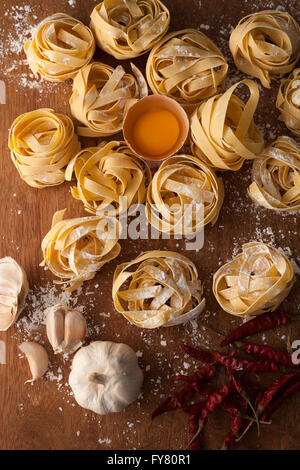 Fettuccine Nudeln italienische Essen Stilleben rustikale Wohnung legen Holz Hintergrund Tagliatelle Alfredo Knoblauch Chili Pfeffer Eigelb Stockfoto