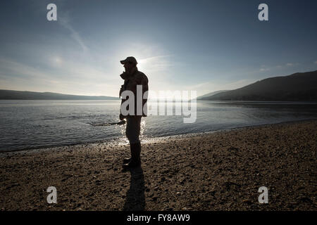 Mann in der Silhouette am Strand von Ardentinny Schottland Stockfoto