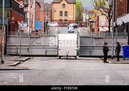 Zwei PSNI Offiziere stehen eine große Metall mobile Polizei Cordon Barriere Absperren einer Straße in Belfast während einer Parade. Stockfoto