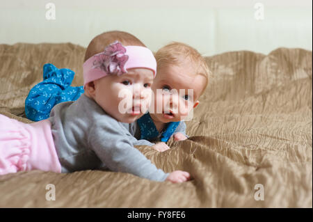 Zwei Babys auf dem Bauch liegend und Grimassieren Stockfoto