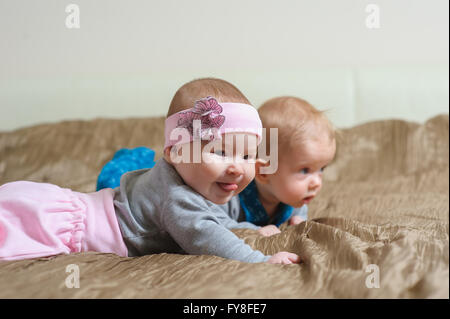 Zwei Babys auf dem Bauch liegend und Grimassieren Stockfoto