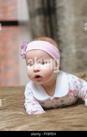 Babymädchen auf Bauch liegend und Grimassieren Stockfoto