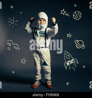Kind mit Raumanzug von Himmelskörpern und Koryphäen umkreist Stockfoto